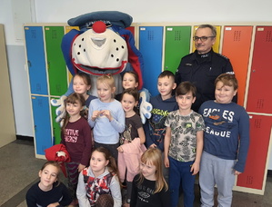 na zdjęciu dzieci pozują wraz z policjantem i sznupkiem do zdjęcia