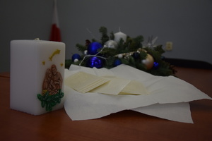 na zdjęciu świeca, opłatki i stroik świąteczny