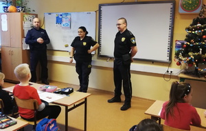 na zdjęciu policjant i strażnicy miejscy w sali szkolnej, w trakcie spotkania z uczniami