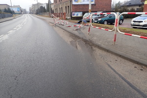na zdjęciu odcinek drogi, na którym widać zniszczone w wyniku kolizji barierki na chodniku, w tle zabudowania i inne pojazdy