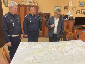 na zdjęciu komendant z zastępcą naczelnika ruchu drogowego i dyrektorem zarządu dróg przy mapie rozłożonej na stole