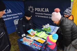 na zdjęciu policjantka w namiocie informacyjnym przy którym stoi dziecko i rodzic