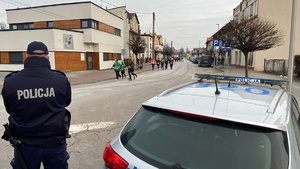 na zdjęciu policjant przy radiowozie w trakcie zabezpieczenia biegu