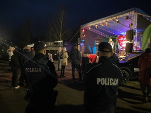 na zdjęciu policjanci obserwujący osoby pod sceną, na której gra zespół