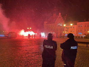 na zdjęciu policjanci obserwują osoby na płycie tarnogórskiego rynku, które odpaliły petardy i race