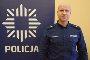 na zdjęciu policjant przy banerze z napisem policja