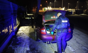 na zdjęciu policjant przy pojeździe z otwartym bagażnikiem w trakcie przeszukania