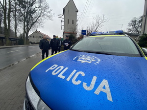 na zdjęciu maska nowego radiowozu, za pojazdem goście w trakcie uroczystości