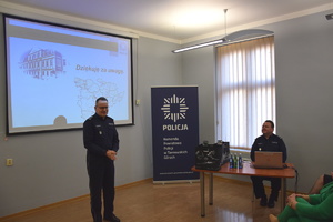 na zdjęciu zastępca komendanta wojewódzkiego w trakcie przemowy w sali narad, w prawej części zdjęcia przy stoliku, na którym leży komputer, siedzi komendant powiatowy