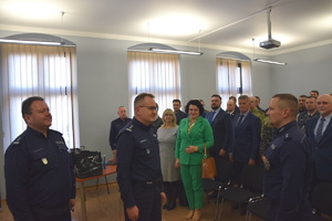 na zdjęciu zastępca komendanta wojewódzkiego przed którym stoi naczelnik prewencji składający meldunek, w lewej części fotografii komendant powiatowy. Za policjantami widownia