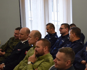na zdjęciu policjanci i inni przedstawiciele służb mundurowych siedzą na krzesłach w sali narad komendy