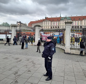 na zdjęciu policjant przed ogrodzeniem zamku królewskiego w warszawie