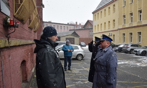 na zdjęciu komendant powiatowy i dyrektor aresztu w trakcie oddawania honoru pod pamiątkową tablicą wmurowaną w budynek aresztu śledczego