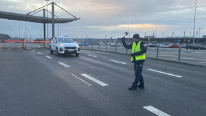 na zdjęciu funkcjonariusz służby celno-skarbowej w trakcie zatrzymywania pojazdu do kontroli, przy bramkach wyjazdowych lotniska