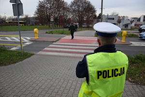 na zdjęciu policjant przy przejściu dla pieszych obserwuje osoby na nim
