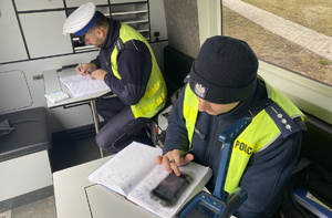 na zdjęciu policjanci w radiowozie w trakcie sporządzania dokumentacji