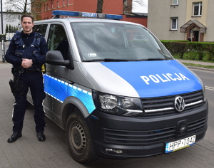 Na zdjęciu policjant stojący przy radiowozie