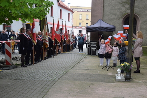 na zdjęciu miejsce uroczystości, gdzie widać występujące dzieci przed publicznością i pocztami sztandarowymi