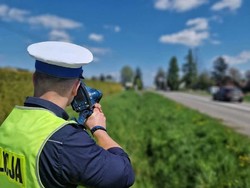 na zdjęciu policjant na pasie zieleni w trakcie czynności pomiaru prędkości