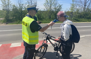 na zdjęciu policjant bada rowerzystę alkomatem