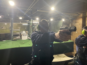 na zdjęciu policjant w słuchawkach i okularach ochronnych w trakcie treningu z bronią, która trzyma obiema rękami przed sobą