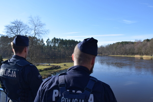 na zdjęciu policjanci obserwują akwen wodny