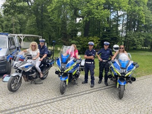 na zdjęciu trzy motocykle policyjne, na których siedzą panie, a obok nich policjanci