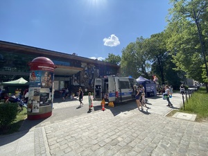 na zdjęciu miejsce pikniku przed tarnogórskim centrum kultury, gdzie widoczne są osoby, policyjny radiowóz i namiot informacyjny