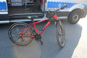 na zdjęciu rower koloru czerwonego przed radiowozem
