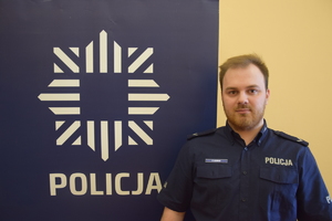 na zdjęciu dzielnicowy przy banerze z napisem policja