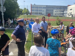 na zdjęciu policjant i dzieci na terenie miasteczka ruchu drogowego