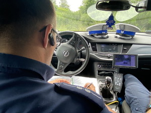na zdjęciu policjant siedzący w radiowozie i sporządzający dokumentacje