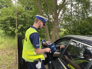 na zdjęciu policjant z miernikiem prędkości przy samochodzie