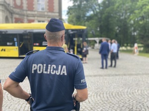 na zdjęciu policjant, przed nim autobus i inni ludzie