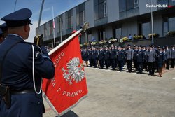 na zdjęciu poczet sztandarowy ze sztandarem oraz policjanci przed budynkiem
