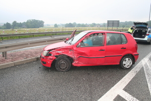 na zdjęciu rozbity czerwony samochód na drodze