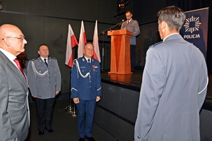 na zdjęciu dowódca uroczystości składa komendantowi wojewódzkiemu meldunek, za nim stoi komendant powiatowy, powyżej na scenie przy mównicy lektor