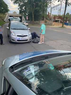 Na zdjęciu widoczny policjant pomagający wymienić koło w samochodzie