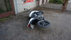na zdjęciu motocykl leżący na boku pod białym murem