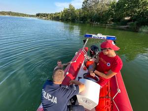 na zdjęciu dzielnicowy i ratownik na motorówce w trakcie rozmowy z osobami na urządzeniach wodnych i w wodzie w trakcie akcji
