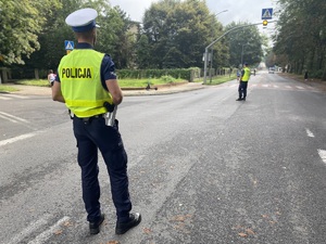 na zdjęciu policjanci na jezdni w trakcie zabezpieczenia biegu