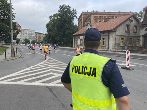 na zdjęciu policjant obserwujący uczestników biegu na trasie