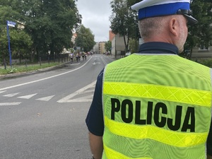 na zdjęciu policjant obserwujący uczestników biegu na trasie