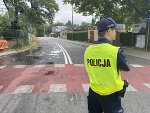 na zdjęciu policjant na jezdni przy trasie biegu