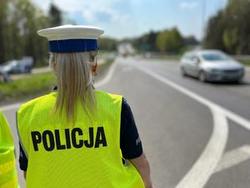 na zdjęciu policjantka stojąca na jezdni, na której przejeżdża samochód osobowy
