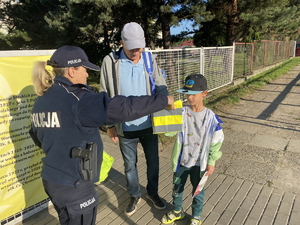 na zdjęciu policjantka przekazuje dzieciom odblaskowe gadżety