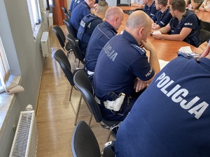 na zdjęciu policjanci siedzący przy stole, w trakcie odprawy do zabezpieczenia imprezy
