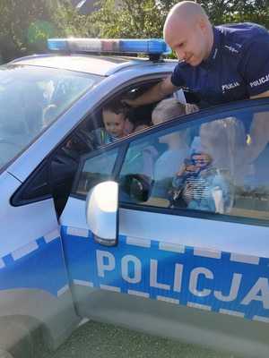 na zdjęciu policjant z dziećmi przy radiowozie