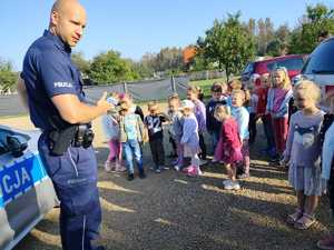 na zdjęciu policjant z dziećmi przy radiowozie