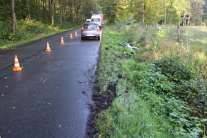 na zdjęciu jezdnia, na której stoi samochód i karetka pogotowia, obok w rowie leży motocykl